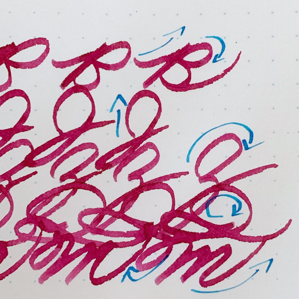 Capital letters written in cursive with bright rose ink